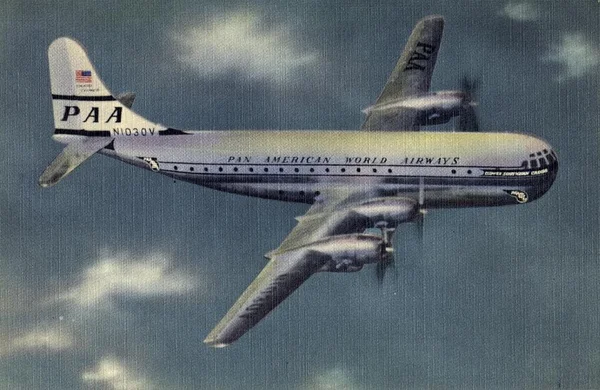 Illustration d'un Boeing 377 Stratocruiser de Pan Am en vol, arborant la livrée historique de la compagnie