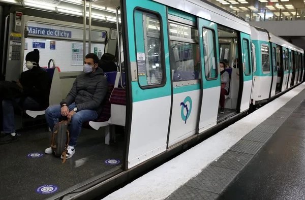 Passagers masqués dans une rame de métro à la station Mairie de Clichy, avec des marquages de distanciation sociale.