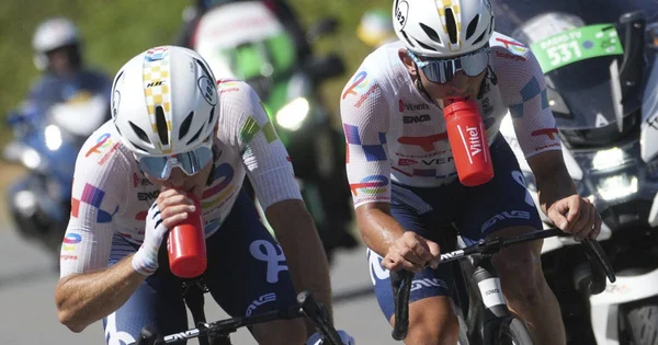 Deux coureurs du Tour de France s'hydratent en pleine course, sous les fortes chaleurs.