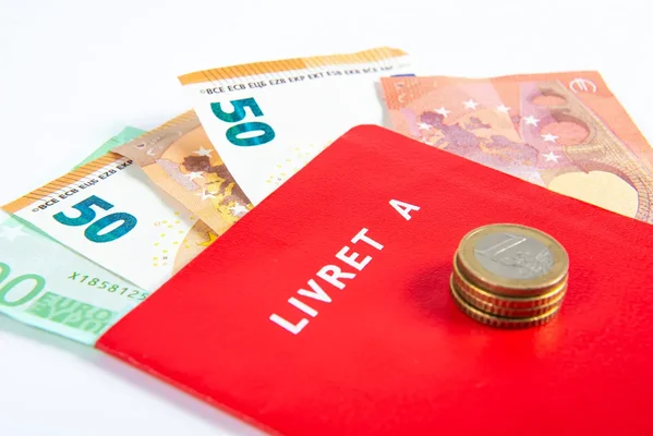 Livret A rouge surmonté de pièces, illustrant les intérêts de l'épargne.
