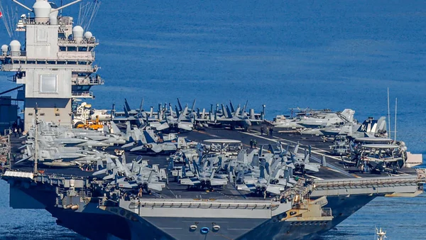 Porte-avions américain déployé au Moyen-Orient, avec de nombreux chasseurs F/A-18 Hornet sur le pont d'envol.