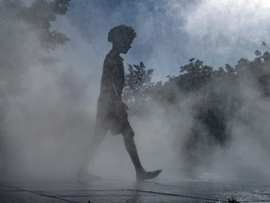 Personne traversant une zone de brume, évoquant la chaleur intense de la canicule.