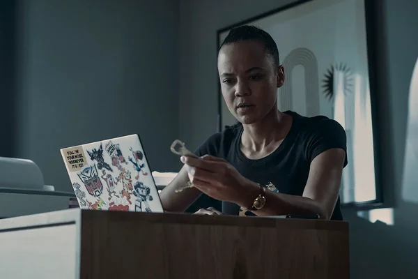 Maria Sten dans le rôle de Neagley, concentrée sur un objet dans un environnement de travail.