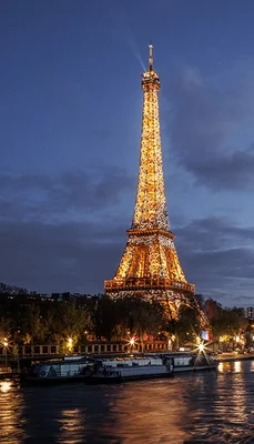 La tour Eiffel illuminée au crépuscule, vue depuis les quais de la Seine.