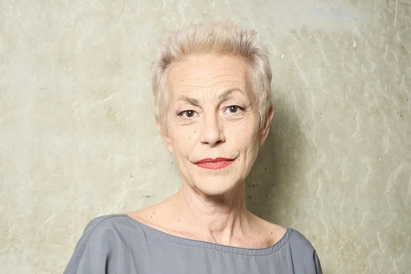 Lio, les cheveux blancs courts et du rouge à lèvres, dans un portrait studio.