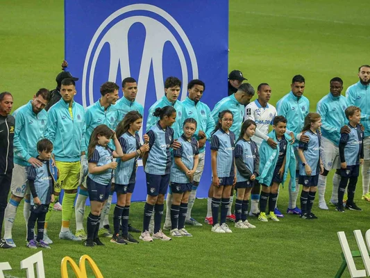 Joueurs de l'OM en survêtement bleu clair avec des enfants mascottes.