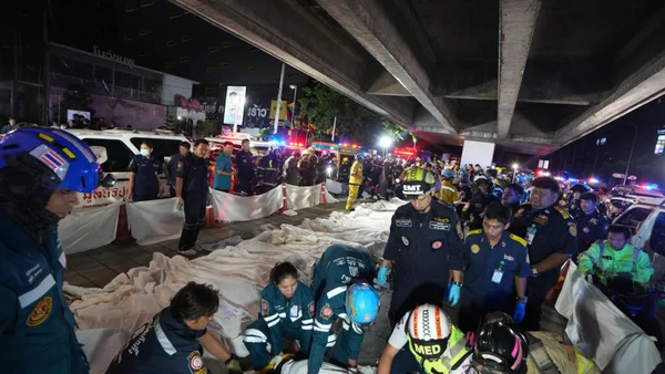 Les secours s'affairent auprès des victimes de l'incendie d'un bar à Bangkok, sous un pont autoroutier.
