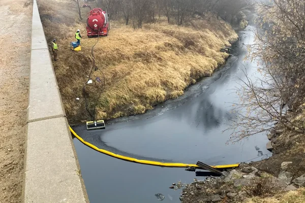 Opérations de nettoyage le long d'une rivière après la fuite de l'oléoduc Keystone au Kansas, avec barrières de confinement.
