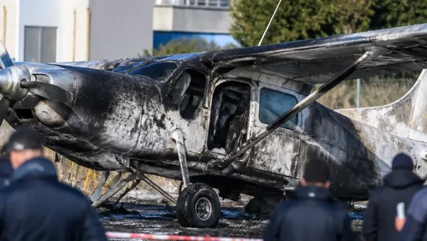 Épave calcinée de l'avion après l'incendie, observée par des enquêteurs.