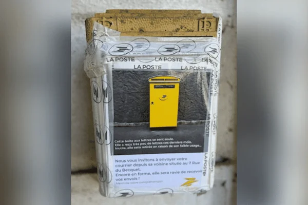 Avis de suppression apposé sur une boîte aux lettres jaune, faute de courrier suffisant.