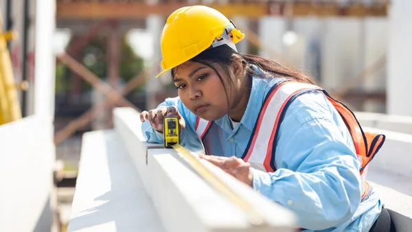 Ouvrière du bâtiment sur un chantier de construction, illustrant le travail des travailleurs étrangers.