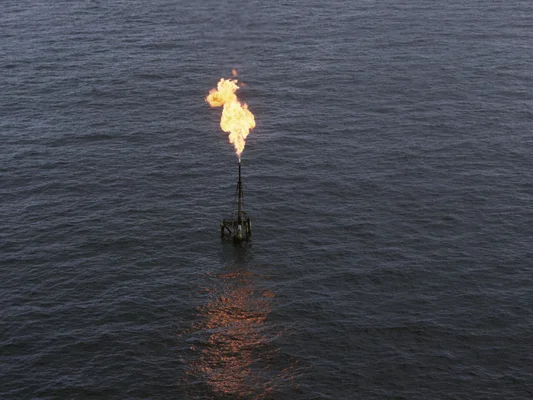 Torche de gaz brûlant sur une plateforme offshore, illustrant les émissions de méthane.