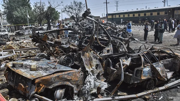 Conséquences de l'attaque à l'explosif d'un train au Pakistan : épave de véhicules et présence des secours.