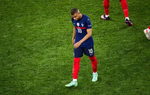 Kylian Mbappé, tête baissée, sur la pelouse lors d'un match des Bleus.