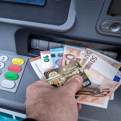 Billets et carte de crédit retirés d'un distributeur automatique.