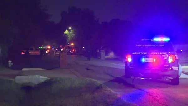 Véhicule de la police de Houston sur une rue résidentielle la nuit, illustrant une scène d'enquête policière.