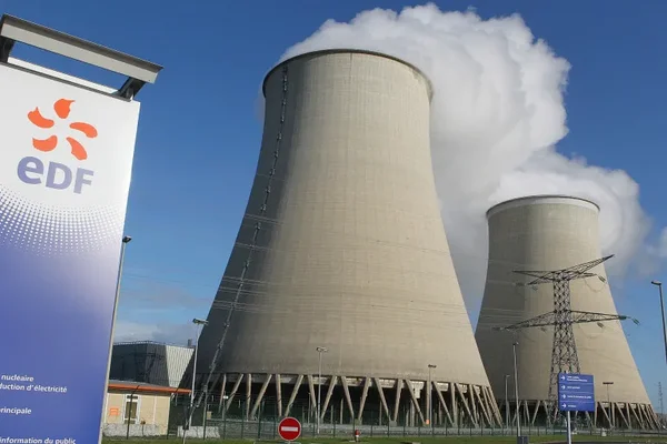 Tours de refroidissement d'une centrale nucléaire EDF avec le logo de l'entreprise au premier plan.