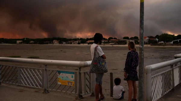 Des habitants de Gironde observent, impuissants, l'immense panache de fumée d'un incendie qui menace leur ville.