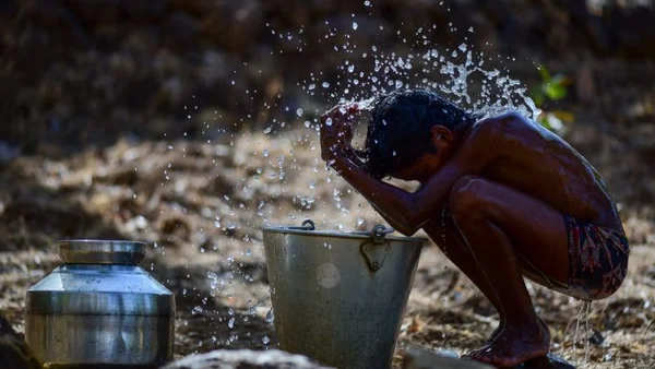 Une personne se rafraîchissant avec un seau d'eau, évoquant les stratégies d'adaptation à la chaleur.