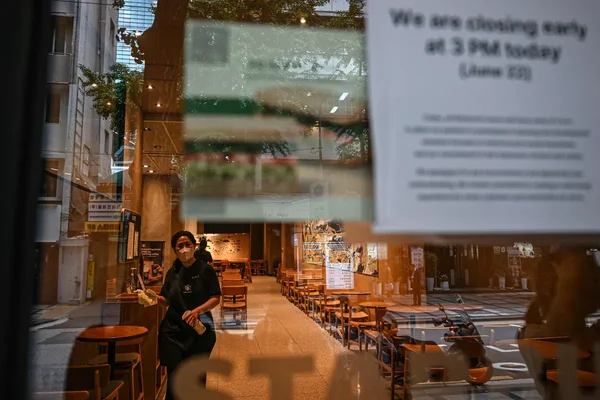 Employé nettoyant un Starbucks vide à Séoul, fermeture anticipée annoncée.