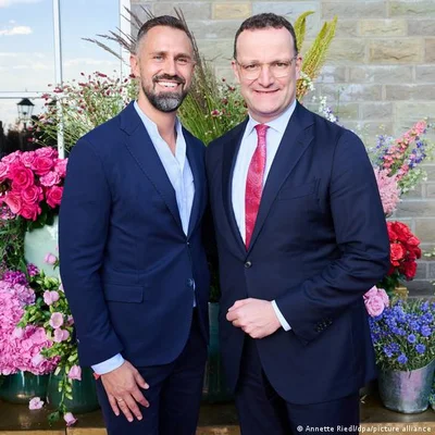 Le député allemand Jens Spahn et son mari posant lors d'une cérémonie, entourés de fleurs.