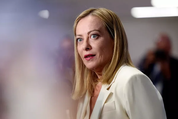 Portrait d'une femme blonde en blazer blanc, évoquant une personne aisée ou une cadre dirigeante.
