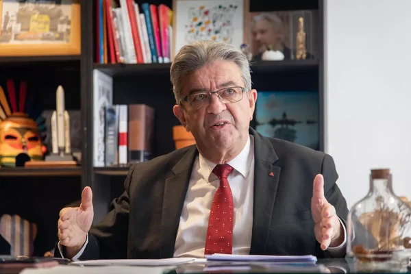 Jean-Luc Mélenchon s'exprimant, entouré de livres, illustrant ses propos sur les médias.