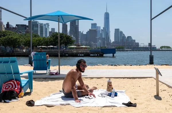 Un homme profite de la plage avec la skyline de New York en toile de fond, alors que la chaleur humide accable la région.