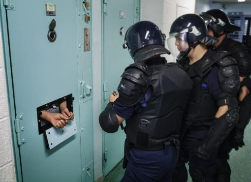 Policiers en tenue anti-émeute devant une cellule au centre pénitentiaire de Condé-sur-Sarthe.