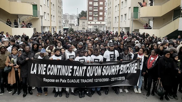 Rassemblement en hommage à Djadje Traoré, avec une banderole commémorative dans une cour résidentielle.