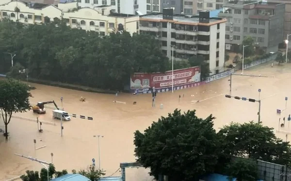 Intersection inondée dans une ville chinoise, avec des véhicules partiellement engloutis par les eaux de crue.