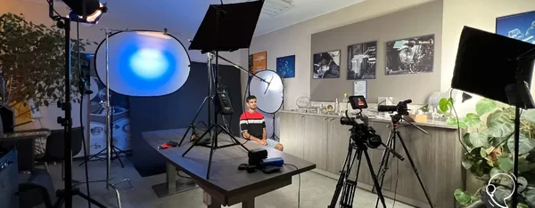 Coulisses d'un tournage en bureau avec équipement professionnel : caméras, lumières et prise de son.