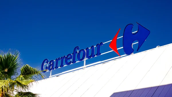 Enseigne Carrefour sur le toit d'un bâtiment, avec palmiers.