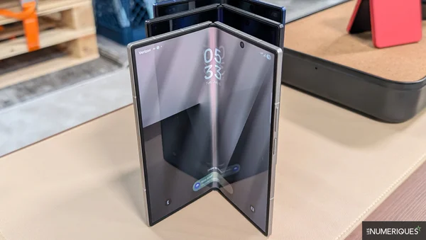 Galaxy Z Fold 8 en mode tente, affichant l'heure, dans un entrepôt.
