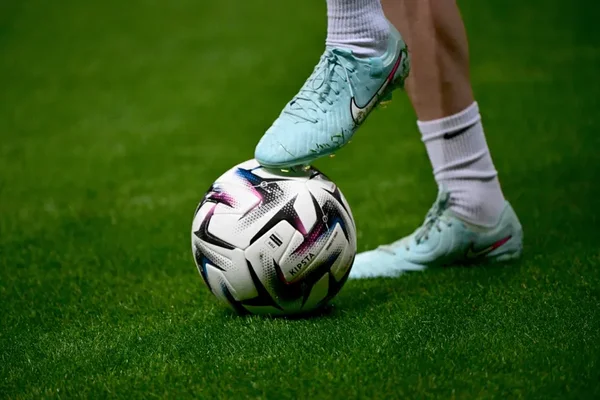 Joueur de football avec le ballon au pied sur la pelouse.