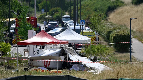 Épave de l'avion accidenté sur le site du crash, avec tentes de secours et véhicules d'urgence.