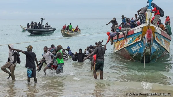 Migrants débarquant d'un bateau sur une plage, illustration du trafic d'êtres humains.