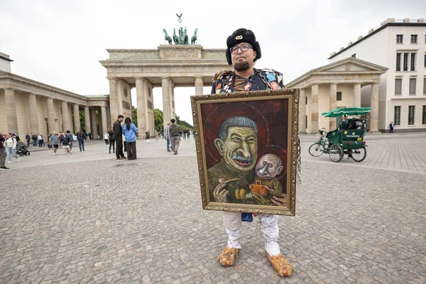 Semyon Skrepetsky devant la porte de Brandebourg à Berlin, présentant sa caricature.