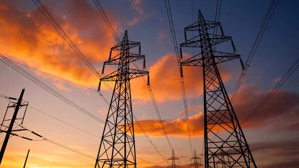 Pylônes électriques et lignes à haute tension au coucher du soleil, représentant les infrastructures d'exportation d'électricité.