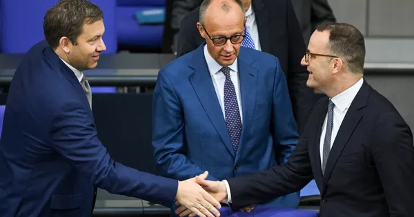 Un député conservateur allemand en costume sombre serrant la main d'un collègue lors d'une rencontre politique.