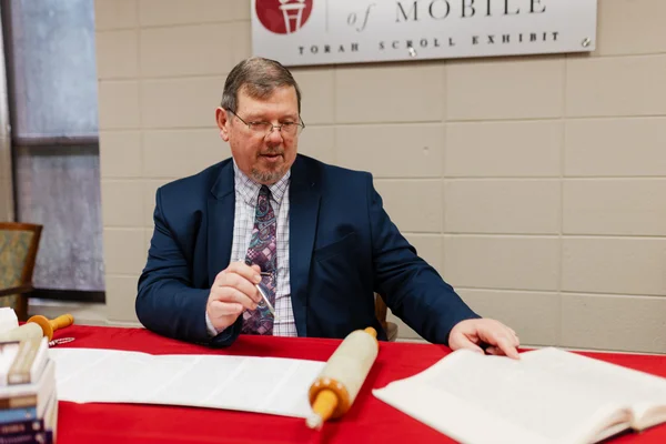 Douglas Wilson examinant un rouleau de la Torah lors d'une exposition à l'Université de Mobile.