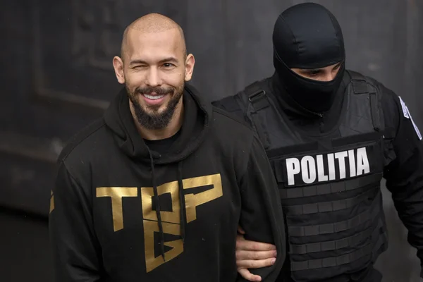 Andrew Tate escorté par un policier roumain après son arrestation.