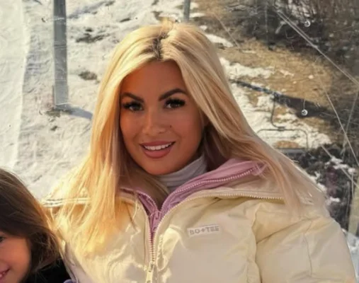 Carla Moreau en tenue d'hiver souriant devant un paysage enneigé.