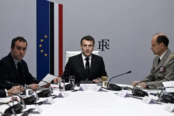 Emmanuel Macron lors d'une réunion diplomatique, avec les drapeaux français et européen en toile de fond.