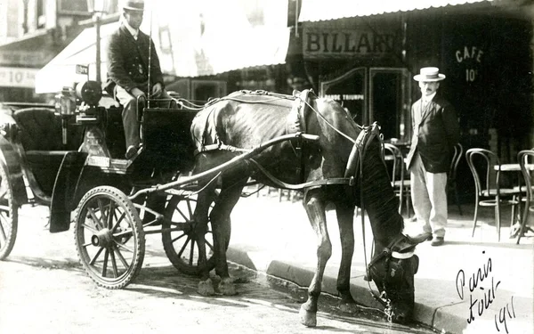 Paris, 1911 : un cheval s’abreuve dans la rue pendant la canicule, sous le regard d’un cocher et d’un passant.
