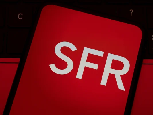 Écran de smartphone arborant le logo SFR sur fond rouge, posé sur un clavier
