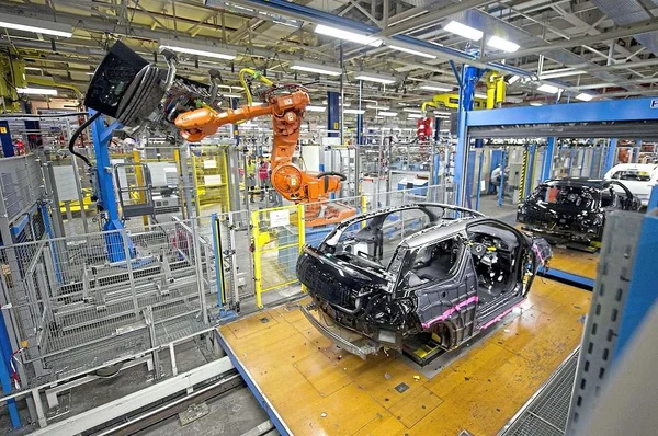 Robotisation dans une usine automobile : un bras robotisé soude un châssis de voiture.