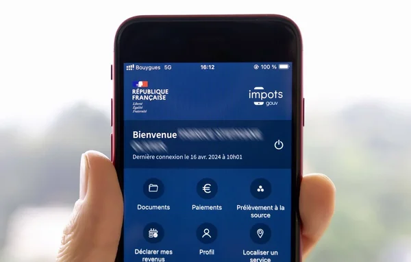 Main tenant un smartphone affichant l'application mobile impots.gouv.
