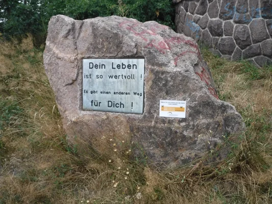 Rocher portant une plaque de prévention du suicide avec les coordonnées de la ligne d'écoute Telefonseelsorge.