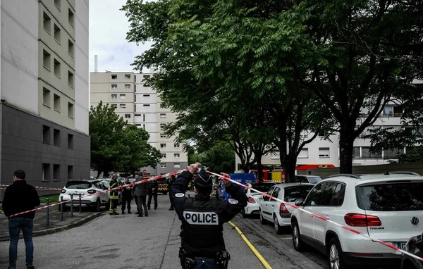 Policier tenant le ruban de sécurité lors de l'intervention après l'incendie criminel à Décines-Charpieu.